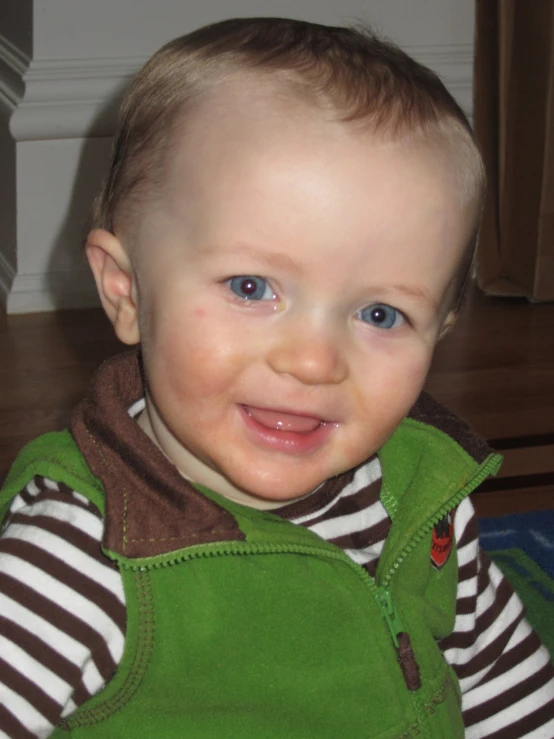 a baby in overalls smiling while wearing a striped shirt