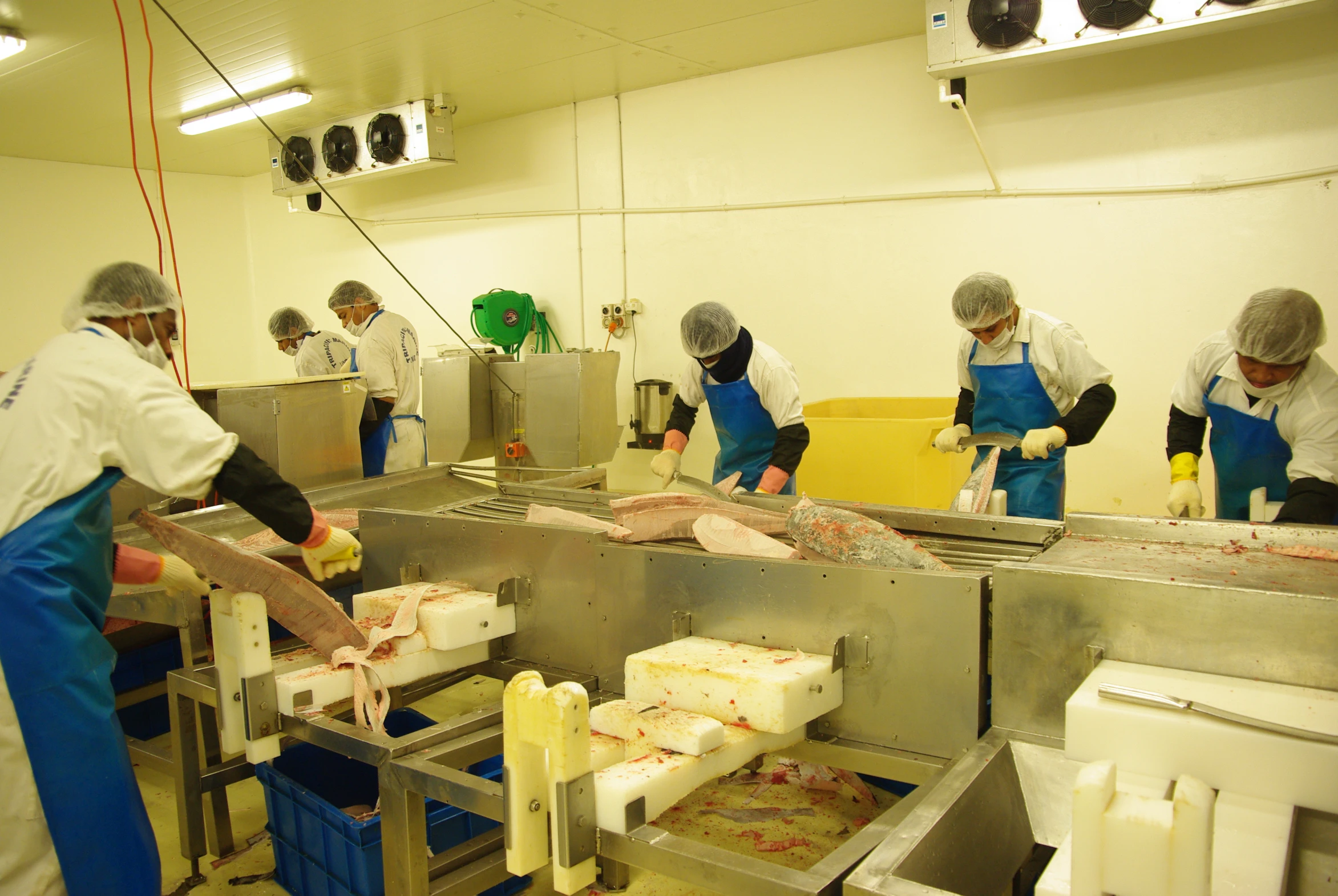 there are several workers making some meat in a room