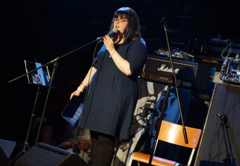 the woman is singing into a microphone as her band plays on stage