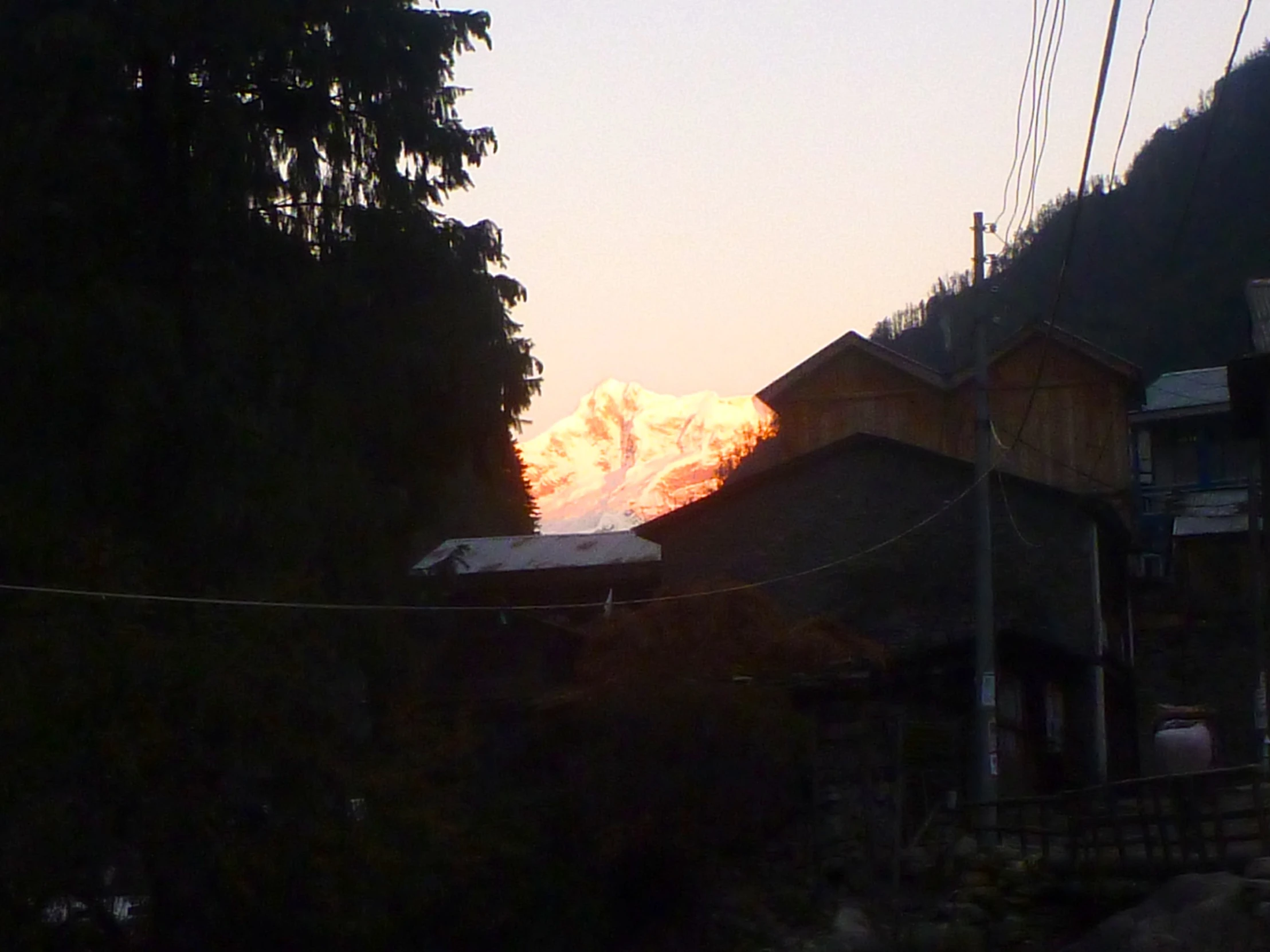 a view of a mountain and the sun through wires