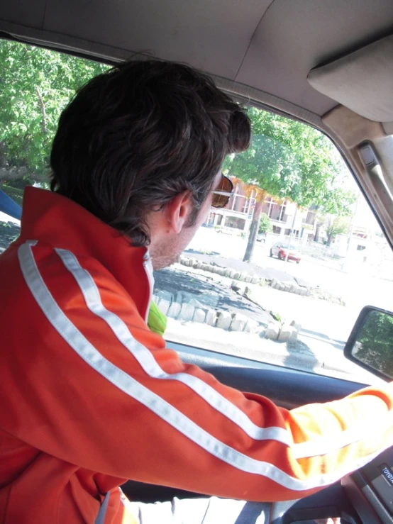 man in orange uniform driving a car in the sun