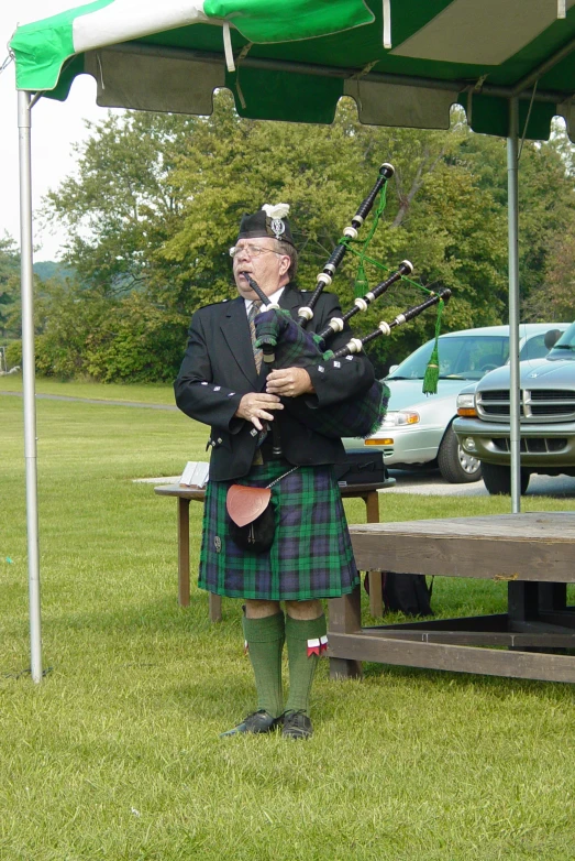 a man in scottish costume playing bagpipes under a tent