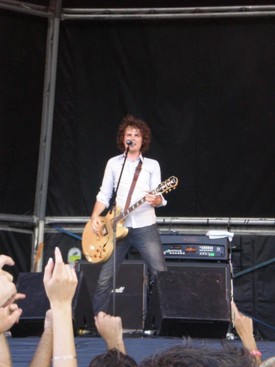 a man playing guitar while standing on a stage