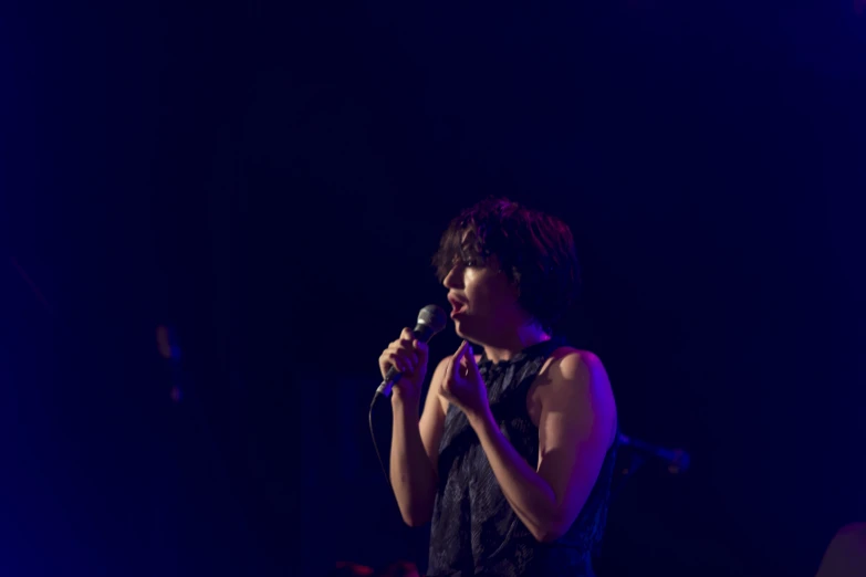 a woman standing on a stage talking into a microphone