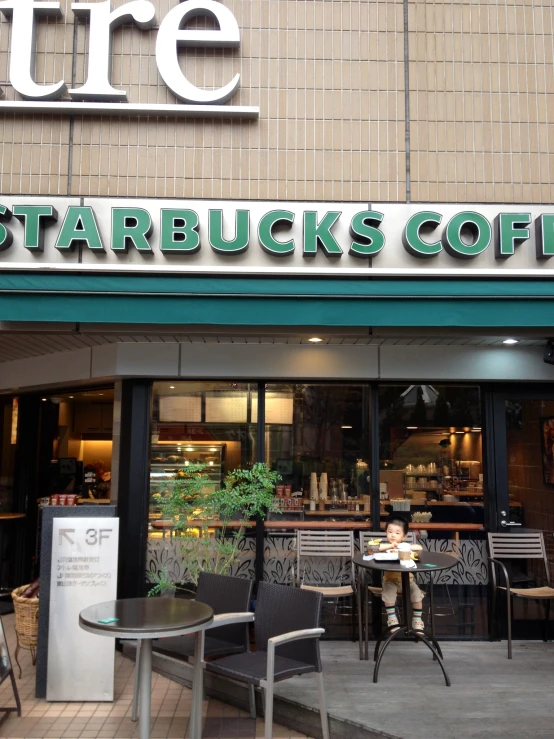 an outside of a starbucks with chairs on the side of the street