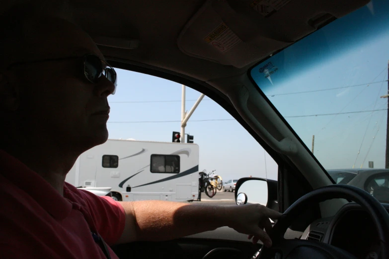 a man sitting in a car next to a parked truck