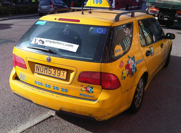 the back end of a yellow taxi with advertising written on it