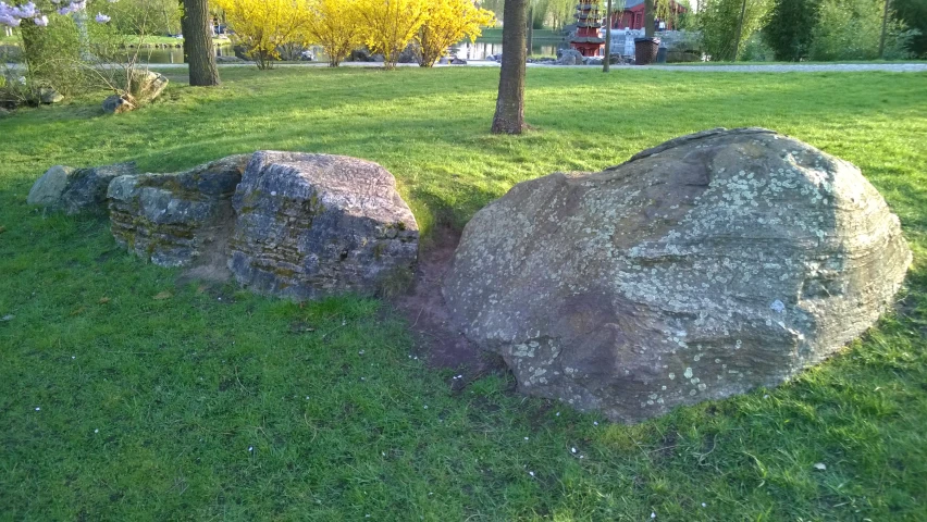 a large rock sitting in the middle of a green field