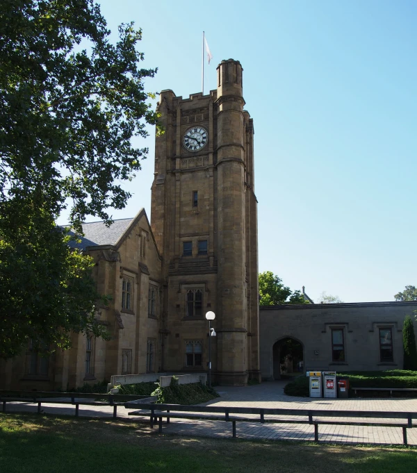 a clock tower stands at the entrance of a stone building