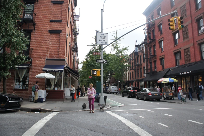 a city street filled with cars and pedestrians next to red brick buildings