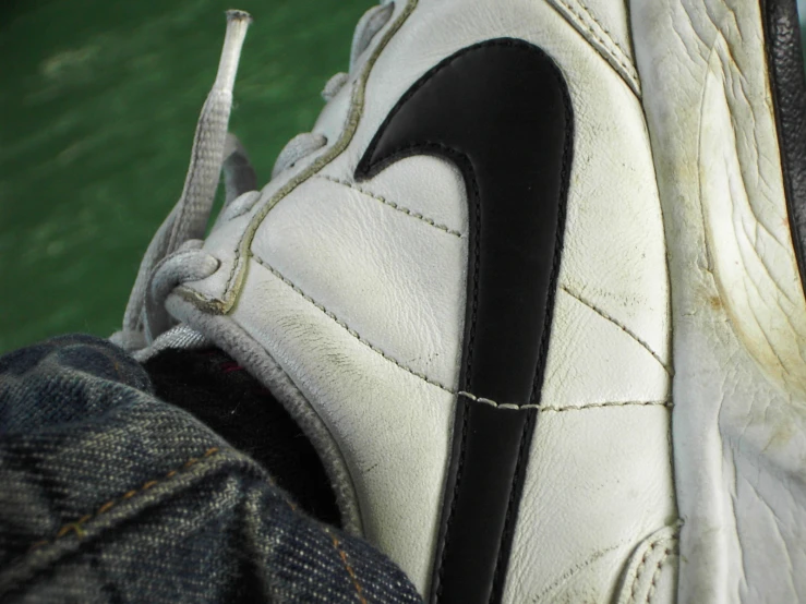a white and black nike shoe sitting on top of someones feet