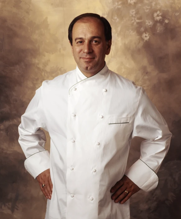 a man in a chef jacket smiles at the camera