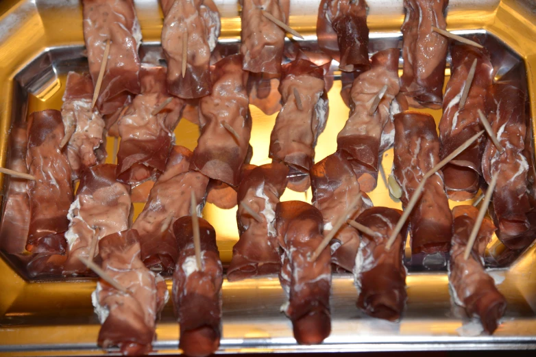 several meats hang from a tray ready for roasting