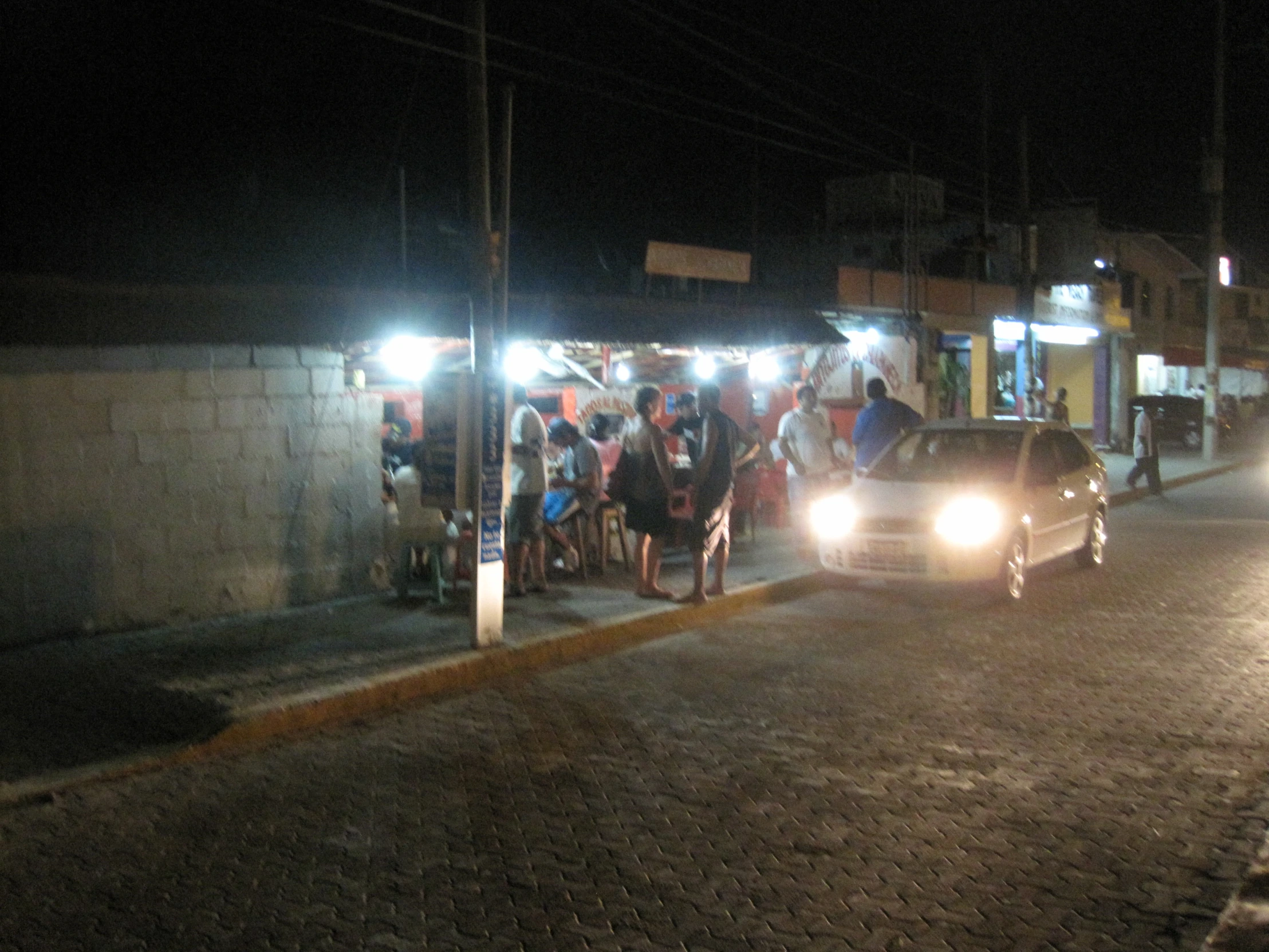 car driving down the street near a line of people on the sidewalk