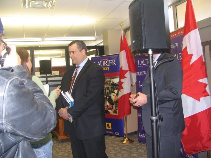 a group of people stand in a room with flags around