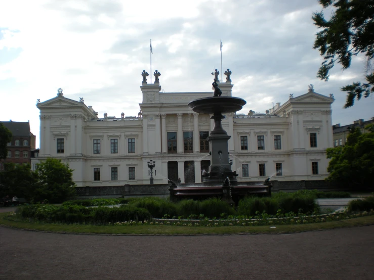 a large white mansion with many statues near by