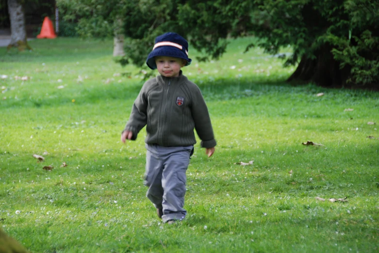 a small boy running across a green park
