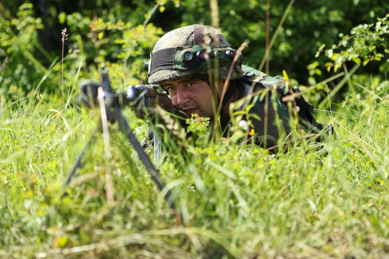 the military soldier is hiding among the tall grass