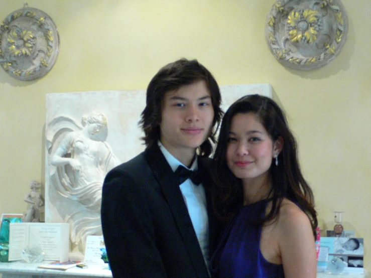 two young people posing in formal attire next to each other