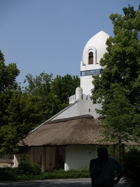 a white building with a thatched roof and a cross