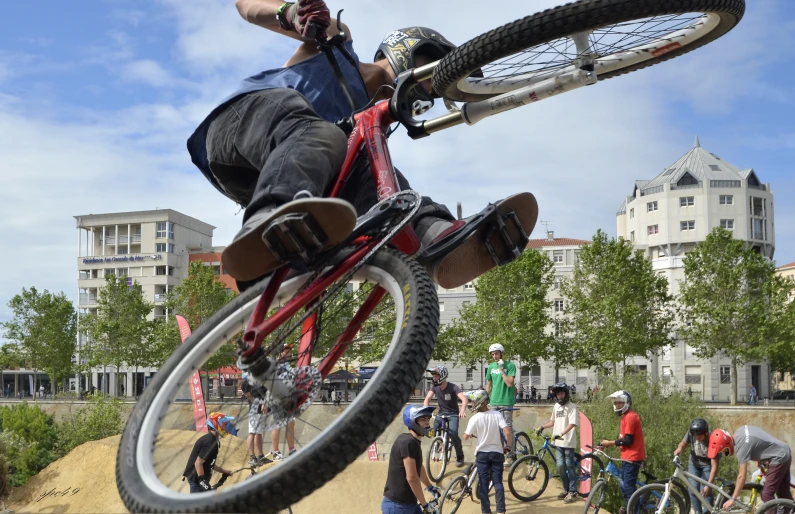 a man who is jumping over a bike with people nearby