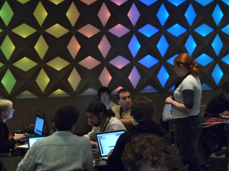 some people sitting at tables and computers with colored lights on them