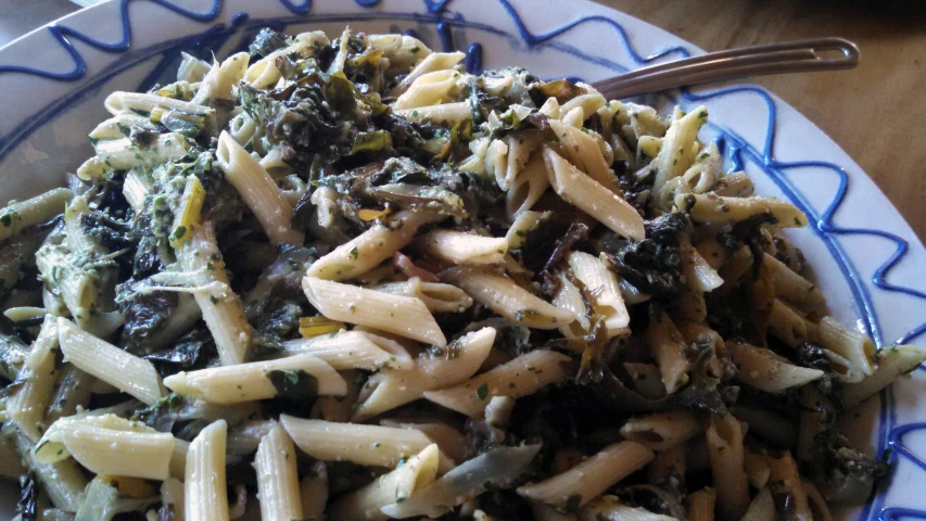 a large bowl filled with pasta and greens