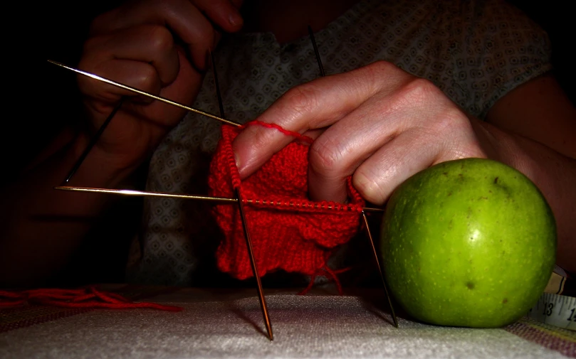 an apple is being knitted with needles and yarn