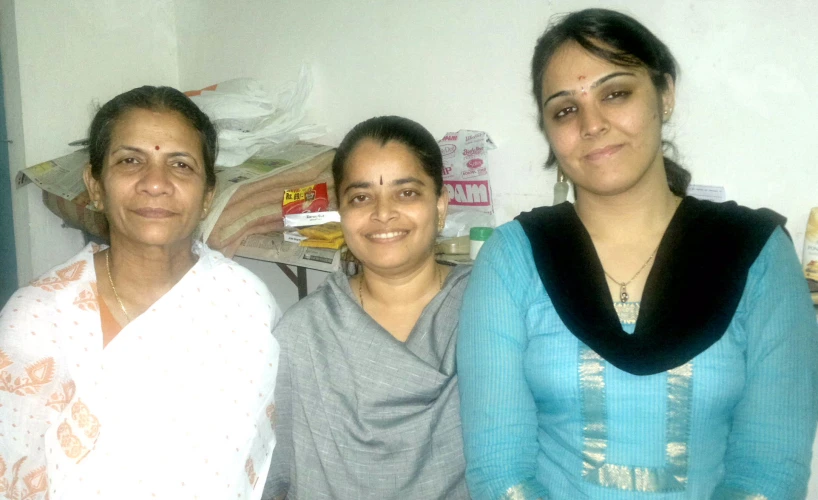 three women are standing in front of a bed