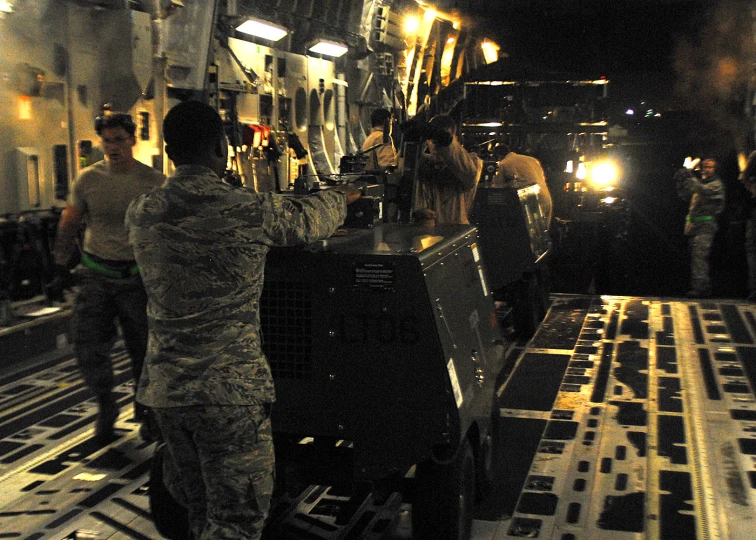 military men stand on tracks near trucks in the dark