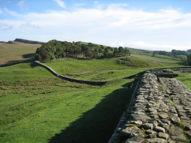 a view of an ancient stone wall with an artificial green pasture