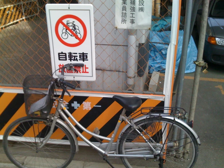 a bike parked next to a fence on the sidewalk