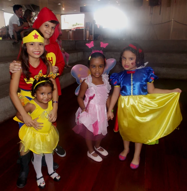 three girls in costumes are standing near two boys wearing costumes