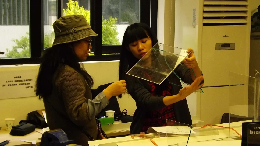 two woman stand together in an office holding up some clear objects