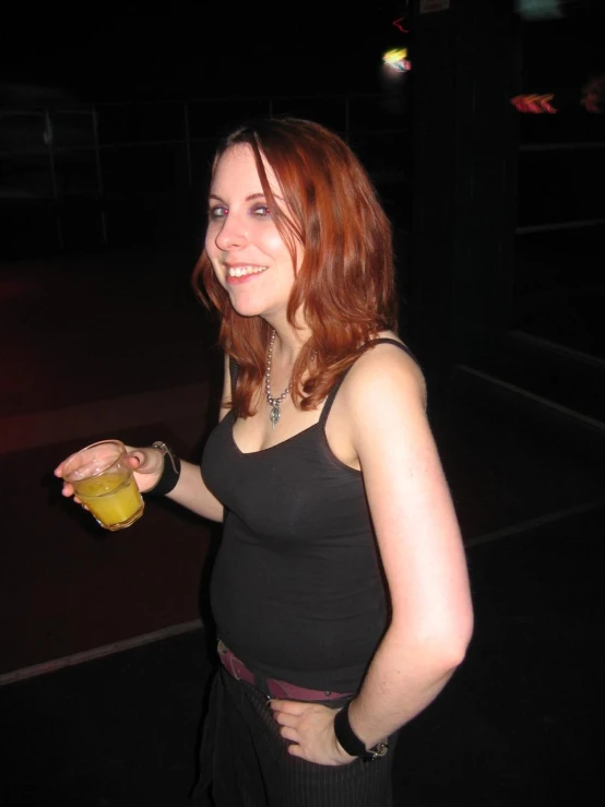 a woman is standing and holding a glass of liquid