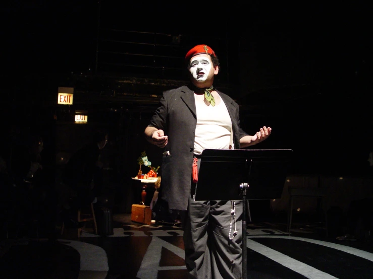 an evil clown wearing his face painted as it stands at the front of a stage