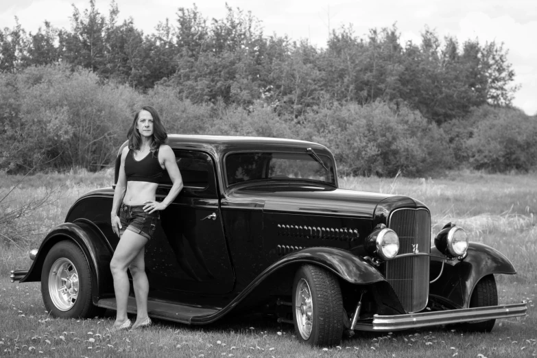a woman in a bikini poses next to an old pickup truck