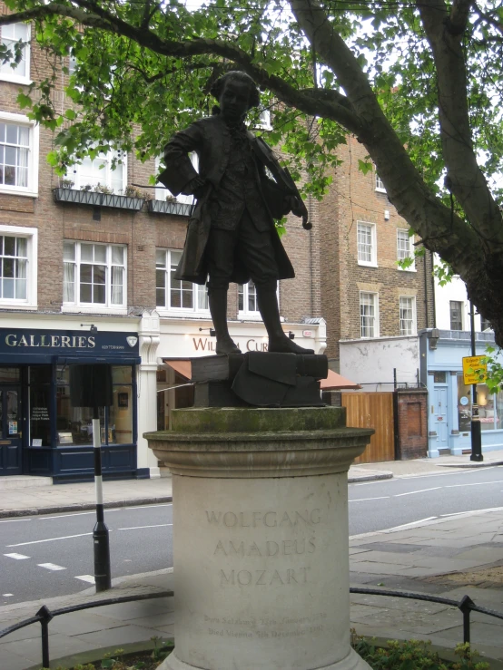 the statue is located near the tree on the side of the street
