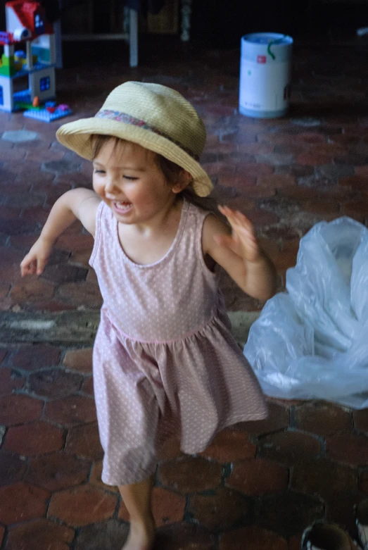 the child in a hat smiles as she walks around