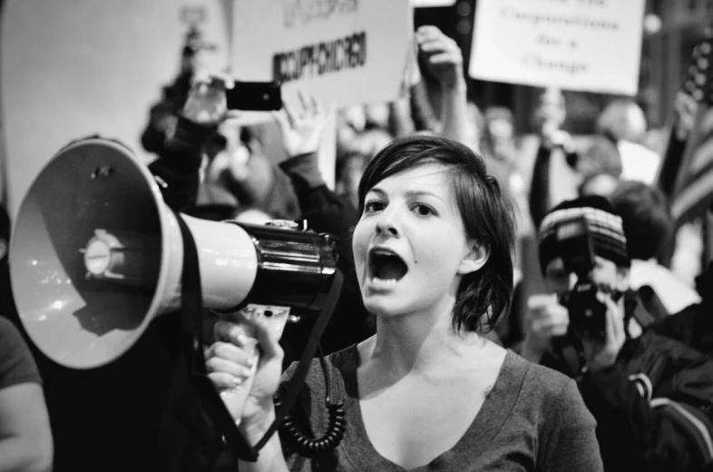 a woman is shouting and holding a speaker