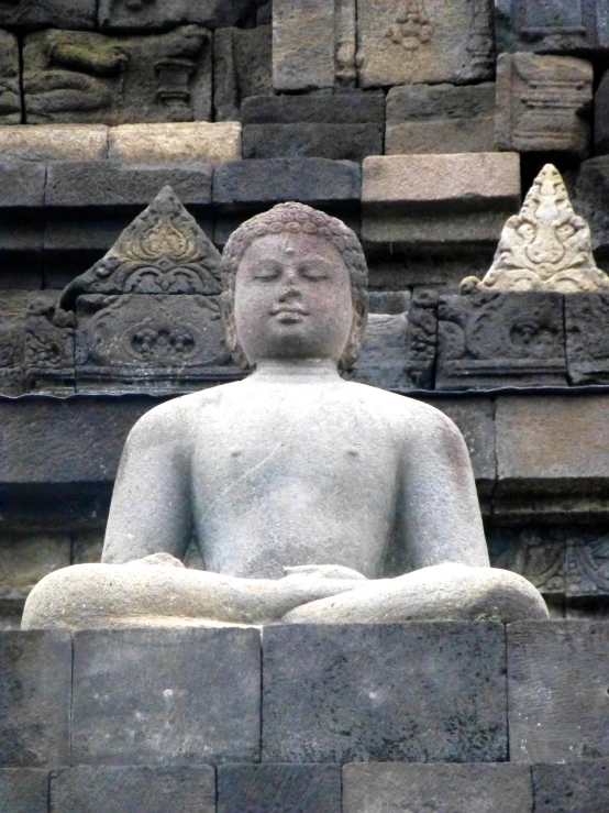 a stone buddha statue is sitting alone