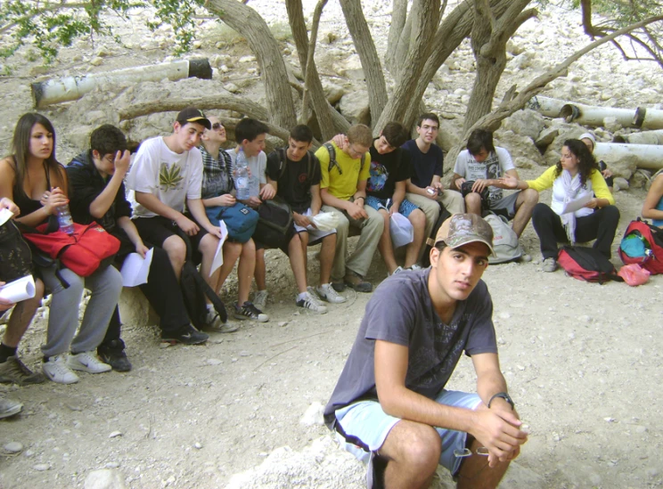 a bunch of people are sitting in front of trees and dirt