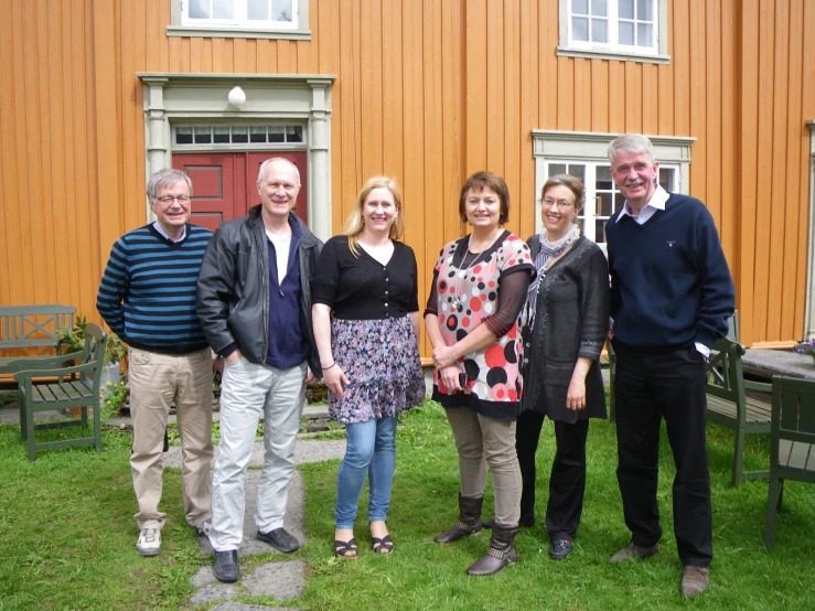 people in front of wooden building standing on green grass