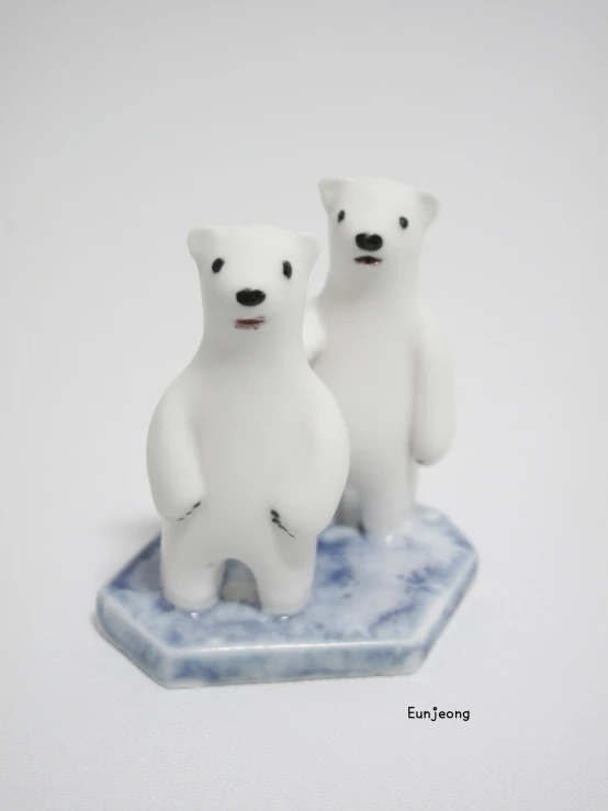 two small white polar bears sitting on a marble base