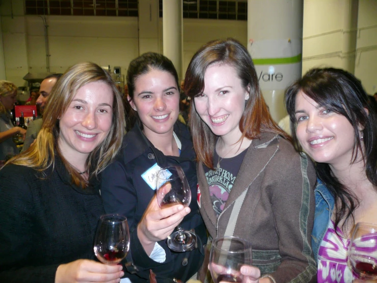 the woman are holding some wine glasses and posing