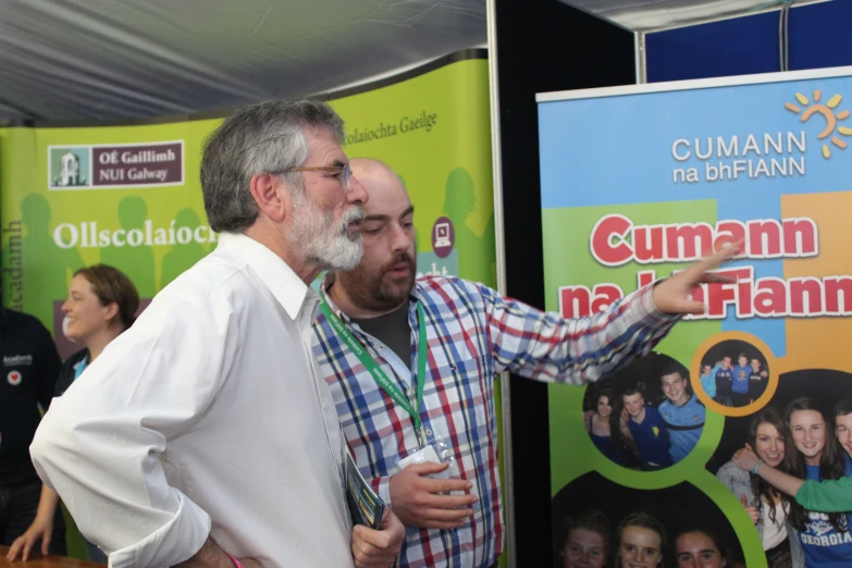 two men are standing at a poster stand