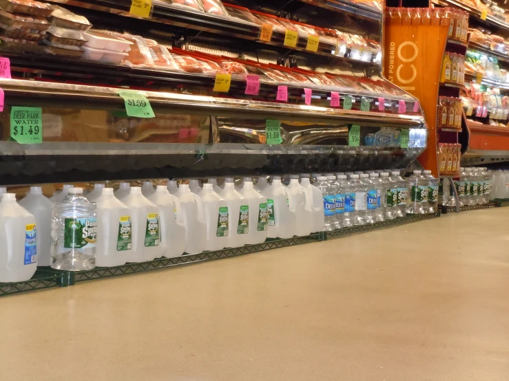 a line of bottles of water sit in a supermarket