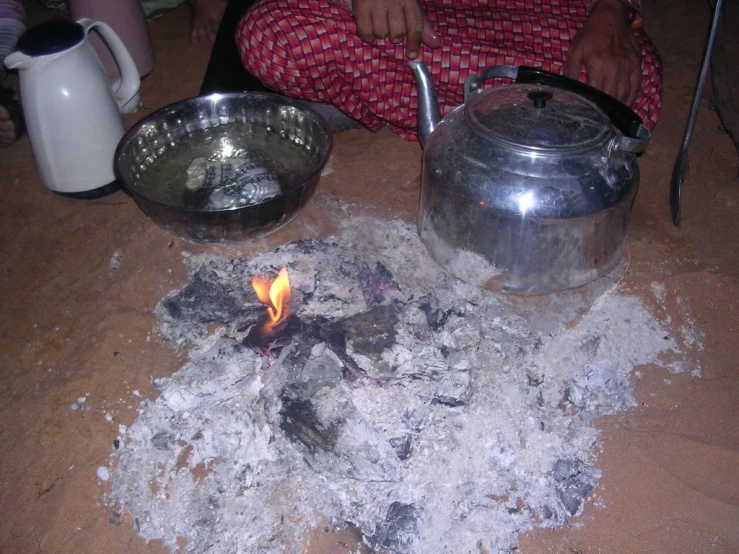 a pot, teapot and bowl sitting on a table top covered in burned material