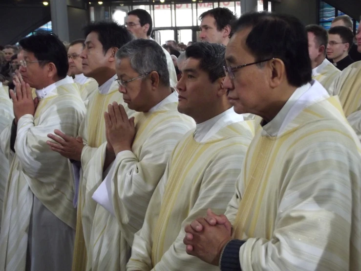 a line of priests standing in formation with their hands clasped