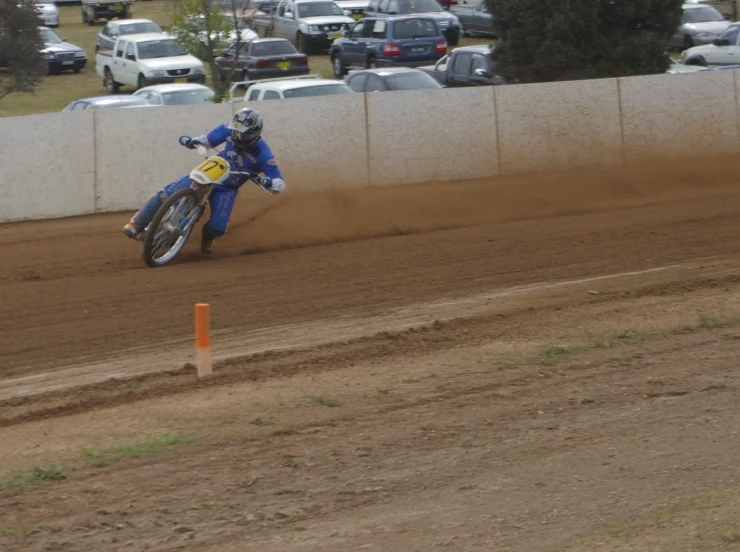 a motorcyclist kicks up dirt on a racing track